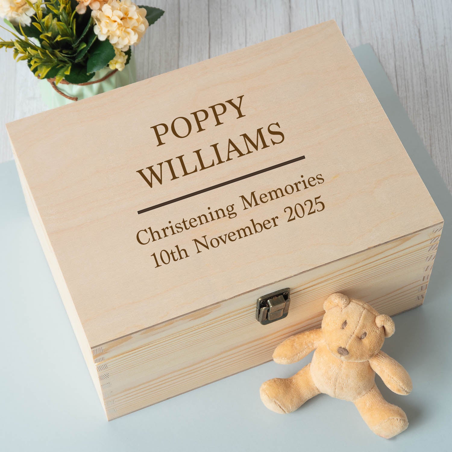 Wooden box engraved with 'Poppy Williams Christening Memories' and a teddy bear on a light surface.