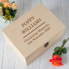 Wooden memory box with engraved text on a wooden surface with flowers and a rose.